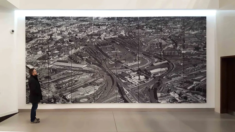 Mural de dieciséis paneles acústicos impresos con una foto aérea en el hall de un edificio