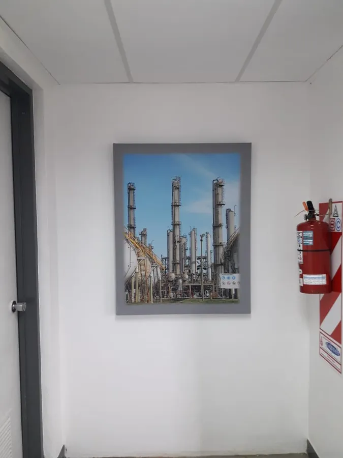 Panel acústico corporativo impreso con la foto de una refinería en un pasillo