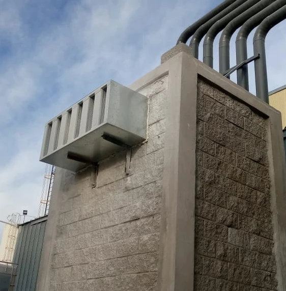 Plenum de mampostería que recibe los escapes metálicos de las bombas de vacío de una planta industrial, con salida protegida por rejilla