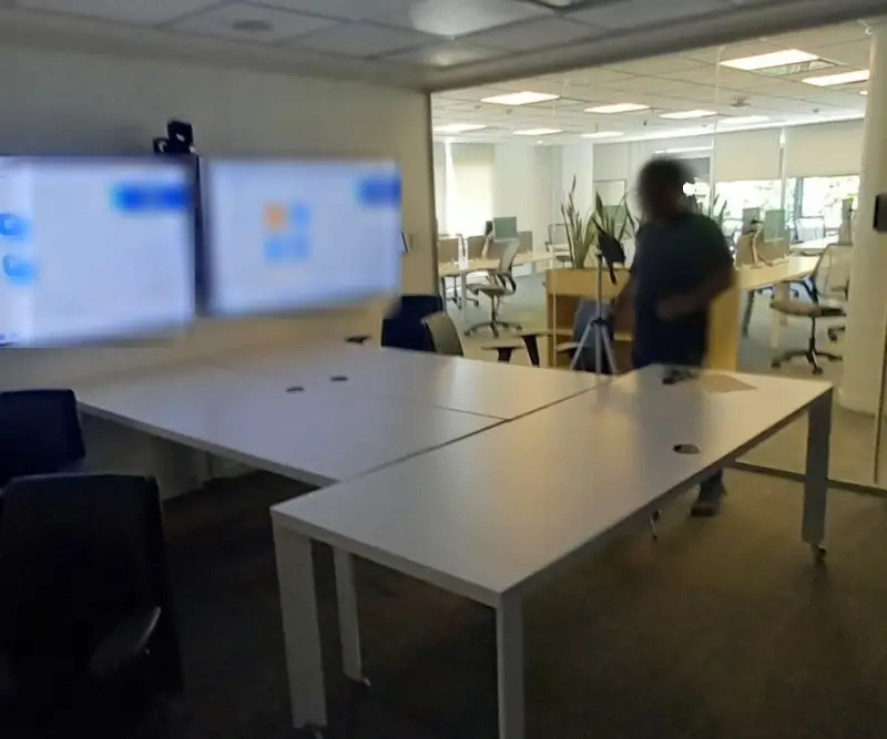Sonómetro sobre trípode durante la medición de reverberación en una sala de videoconferencia